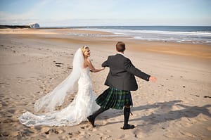 Happy newlyweds at beach overlooking bass rock