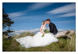Newlyweds kissing against blue sky