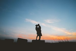 Silhouette of newlyweds kissing against sunset